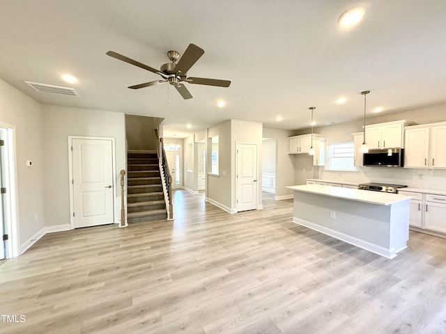 kitchen with recessed lighting, stainless steel microwave, range, light wood finished floors, and visible vents