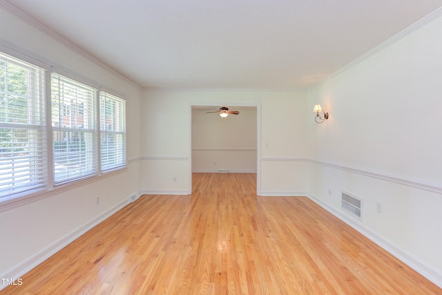 unfurnished room featuring crown molding, light wood-style flooring, a ceiling fan, baseboards, and visible vents