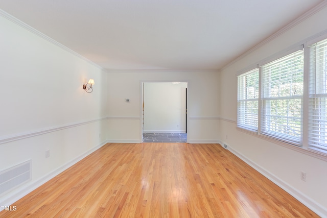 unfurnished room featuring crown molding, baseboards, light wood-style flooring, and visible vents