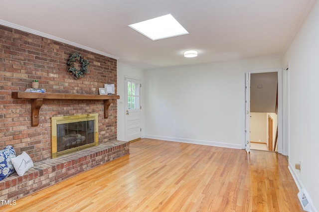 unfurnished living room with a skylight, baseboards, and wood finished floors
