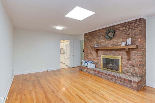 unfurnished living room featuring a brick fireplace, baseboards, ornamental molding, and wood finished floors