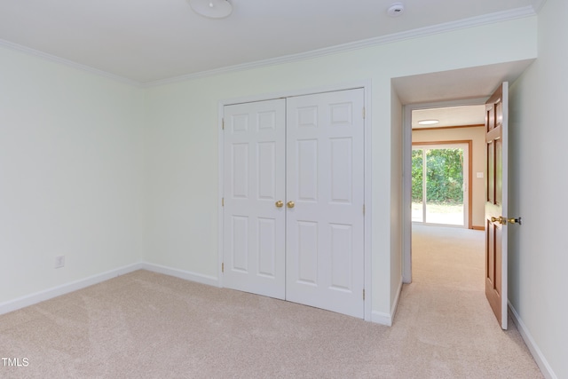 unfurnished bedroom with crown molding, carpet, baseboards, and a closet