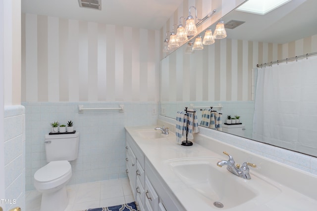 bathroom featuring visible vents, a sink, wainscoting, and wallpapered walls