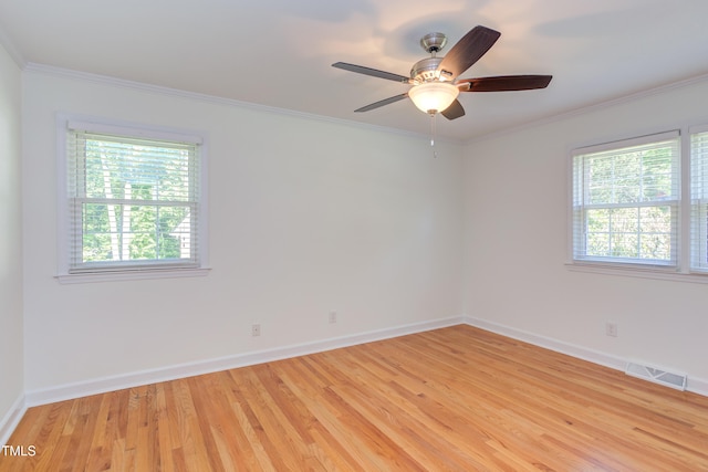spare room featuring baseboards, ornamental molding, light wood-type flooring, and visible vents