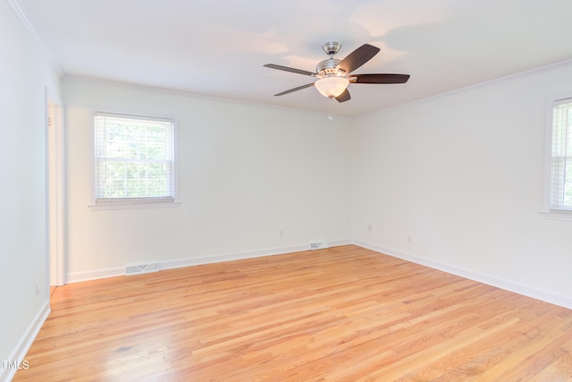 spare room with visible vents, crown molding, light wood-style floors, baseboards, and a ceiling fan