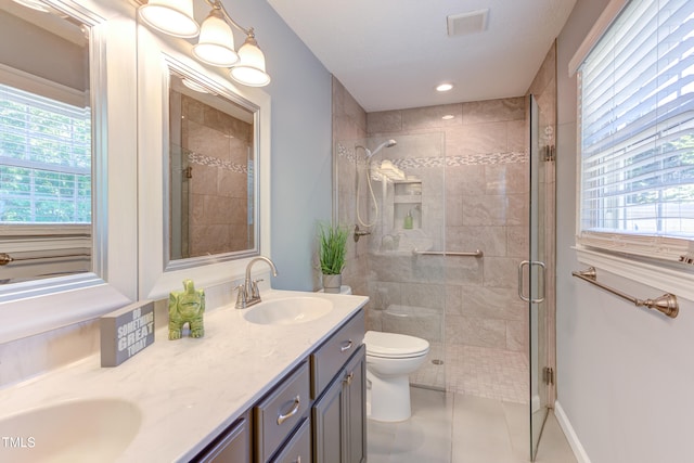 full bath with a sink, toilet, plenty of natural light, visible vents, and a stall shower