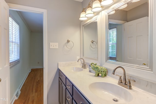 full bath with a sink, double vanity, wood finished floors, and visible vents