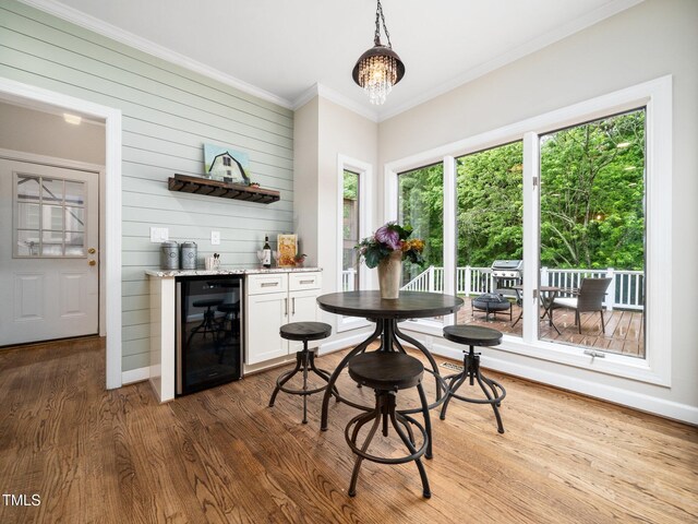 12823 Summerwind Trl, Rougemont, NC 27572 - dining area with beverage cooler, a dry bar, wood finished floors, crown molding, and wood walls