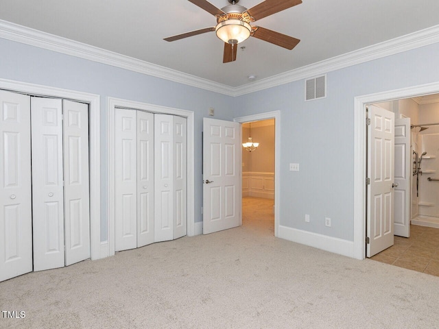 unfurnished bedroom featuring visible vents, carpet floors, baseboards, multiple closets, and ornamental molding