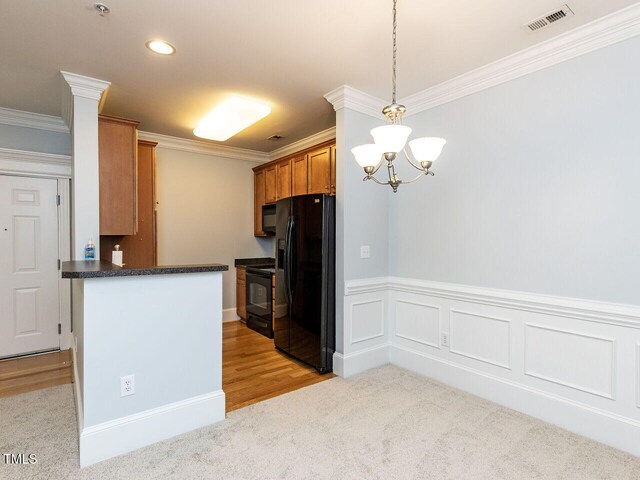 kitchen with crown molding, dark countertops, light colored carpet, visible vents, and black appliances