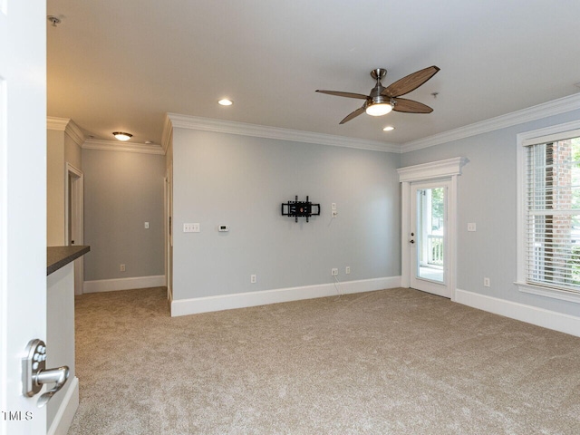 empty room with crown molding, baseboards, a ceiling fan, and light colored carpet