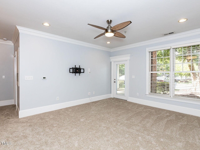 carpeted empty room with visible vents, ornamental molding, a ceiling fan, and a healthy amount of sunlight