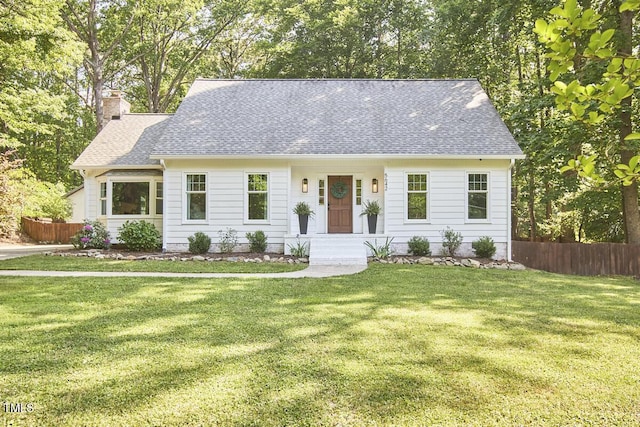 new england style home with a front lawn, fence, and a chimney