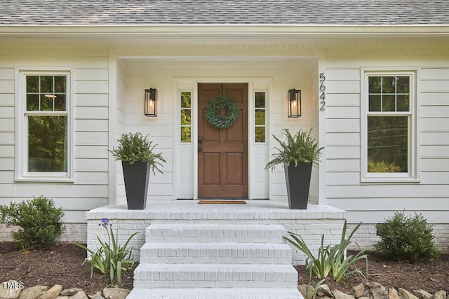 view of exterior entry featuring roof with shingles