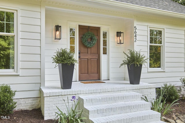 property entrance featuring covered porch and roof with shingles