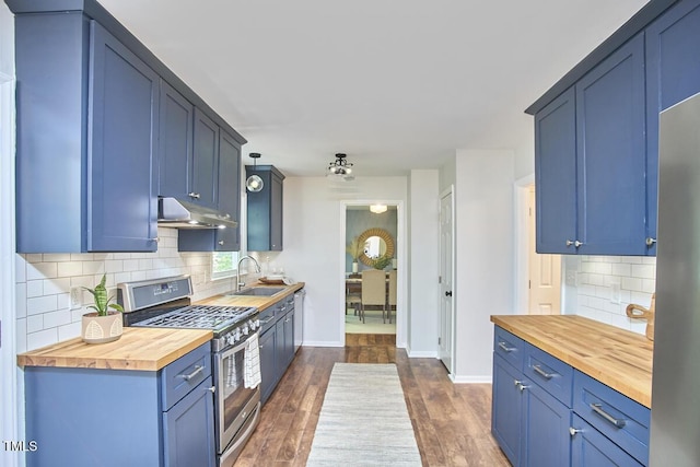 kitchen featuring stainless steel gas stove, a sink, baseboards, under cabinet range hood, and butcher block countertops