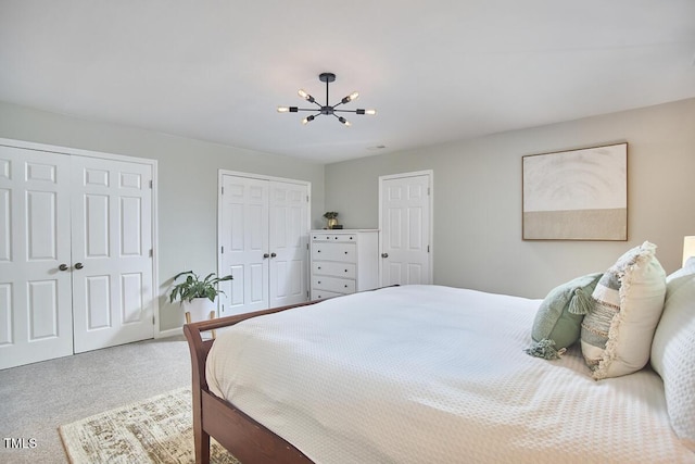 carpeted bedroom with multiple closets, baseboards, and a notable chandelier