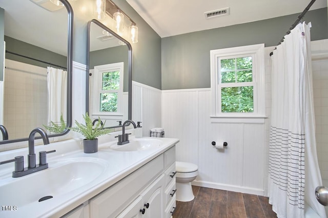 full bath with a sink, a wainscoted wall, toilet, and visible vents
