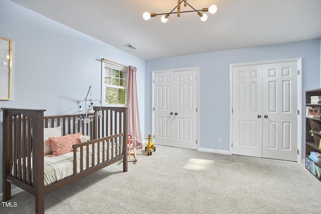 bedroom with visible vents, carpet floors, two closets, baseboards, and a notable chandelier