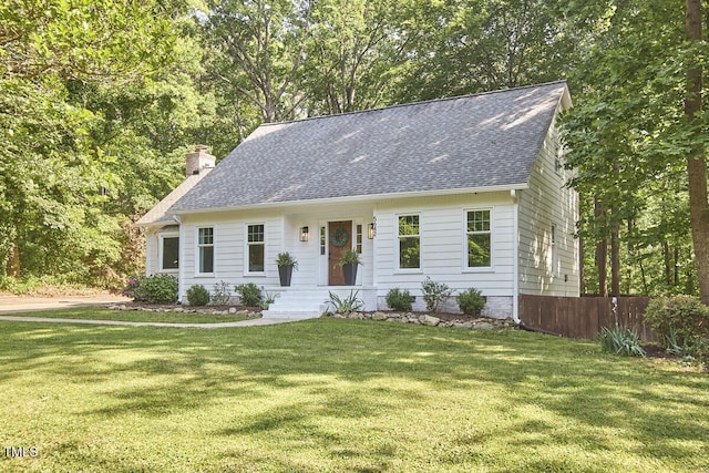 view of front of house featuring a front yard, fence, a chimney, and roof with shingles