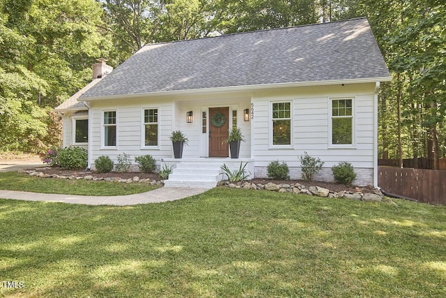 ranch-style home with fence, a shingled roof, a front yard, and a chimney