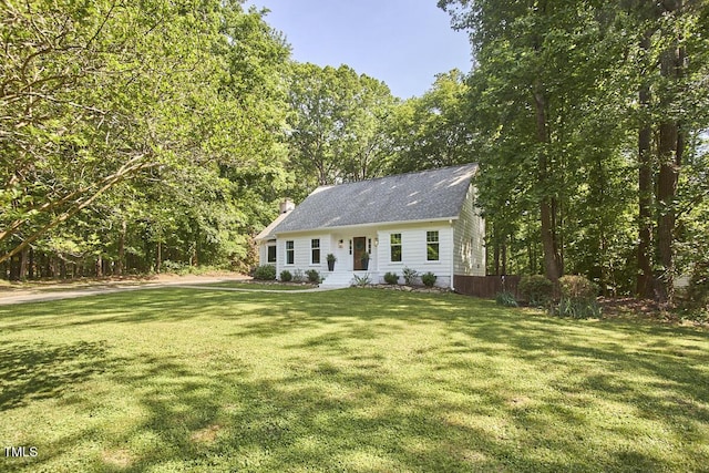 cape cod-style house featuring a chimney and a front yard