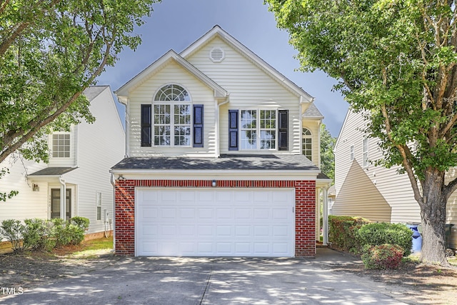 traditional home featuring brick siding, an attached garage, and driveway