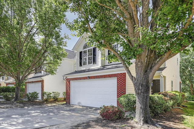 view of front facade featuring a garage, driveway, and brick siding