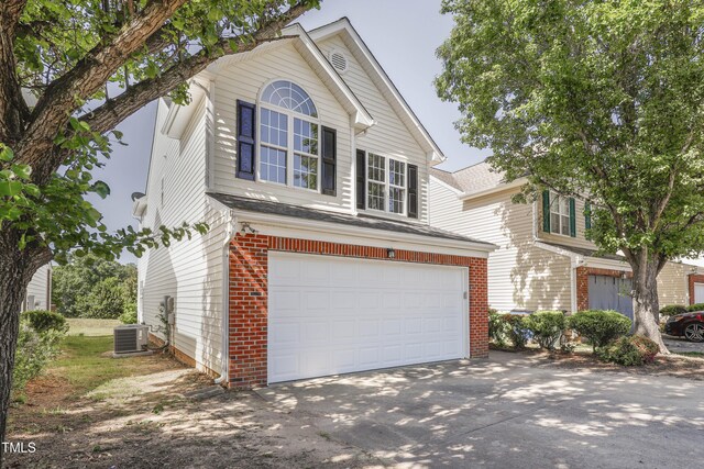 traditional home featuring concrete driveway, brick siding, and a garage