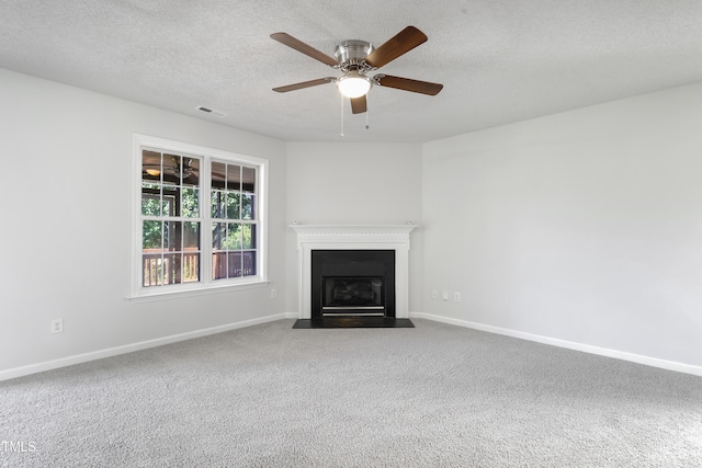 unfurnished living room with carpet floors, a fireplace with flush hearth, a textured ceiling, and baseboards