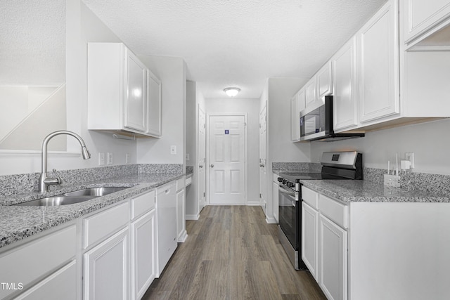 kitchen with white cabinets, appliances with stainless steel finishes, dark wood-style floors, and a sink