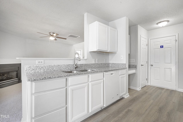 kitchen featuring white dishwasher, ceiling fan, a sink, a textured ceiling, and visible vents