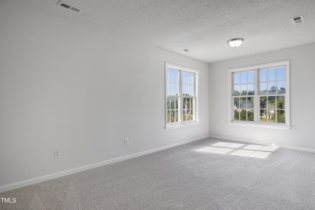 carpeted empty room with a textured ceiling, baseboards, and visible vents