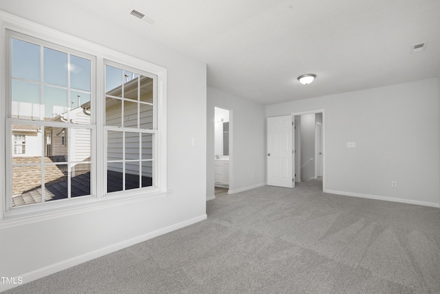 carpeted spare room featuring baseboards and visible vents