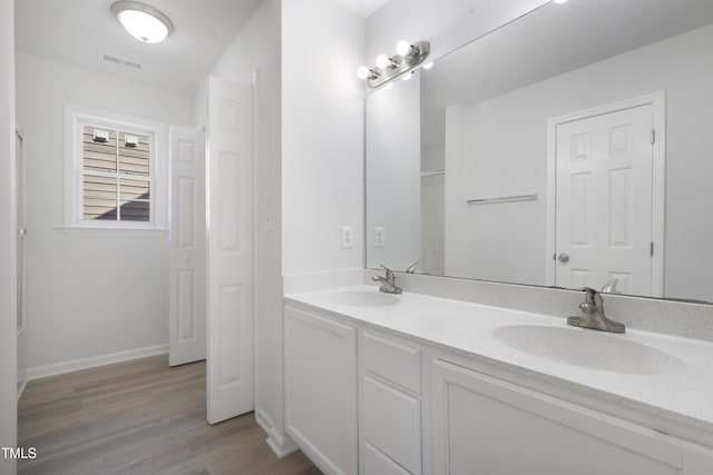 full bathroom with visible vents, a sink, wood finished floors, and double vanity