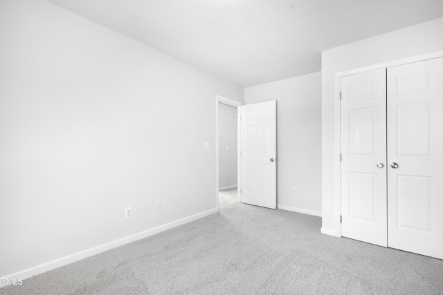 unfurnished bedroom featuring baseboards, carpet flooring, and a closet