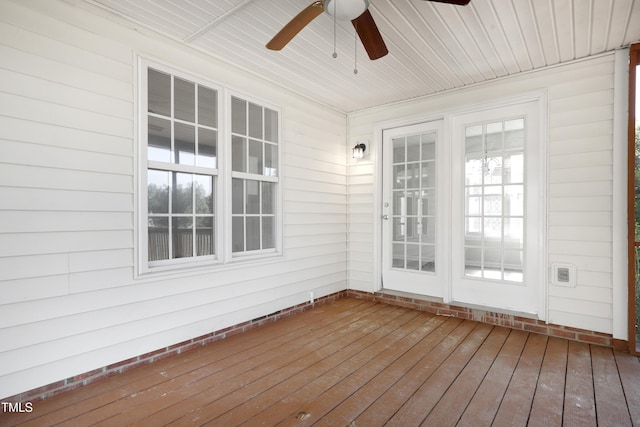 unfurnished sunroom with wooden walls, a ceiling fan, and hardwood / wood-style flooring