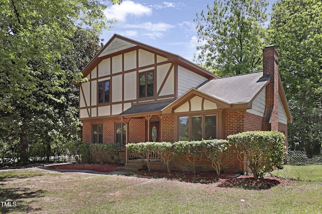 101 Atchison St, Garner, NC 27529 - tudor-style house featuring fence, a front yard, a chimney, brick siding, and a shingled roof