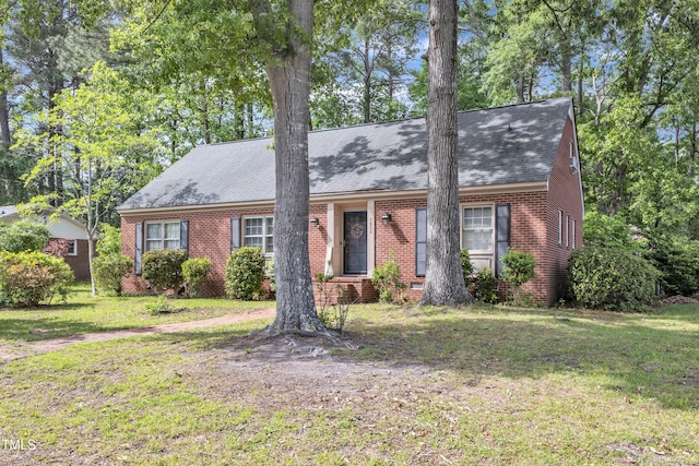 view of front of home with brick siding, a front yard, and roof with shingles
