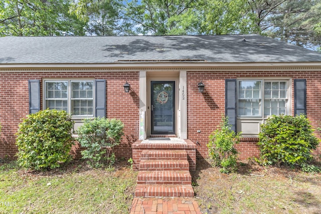 entrance to property with brick siding and roof with shingles