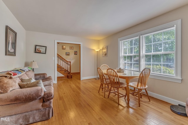 dining room featuring baseboards, stairs, a healthy amount of sunlight, and light wood-type flooring