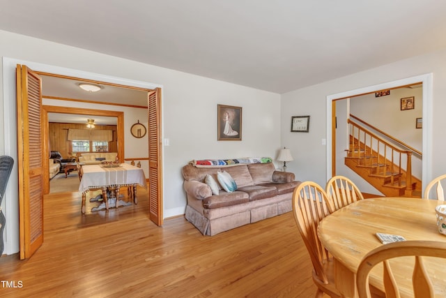 dining room with stairs, baseboards, and light wood-style flooring
