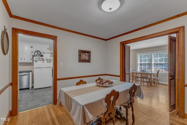 dining room featuring baseboards, ornamental molding, and light wood-type flooring