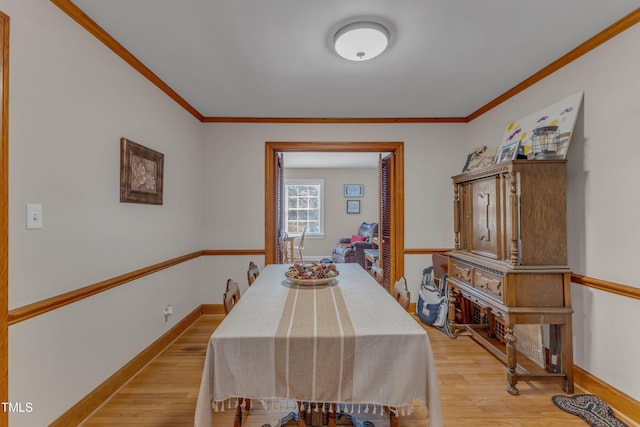 dining area with baseboards, ornamental molding, and light wood finished floors