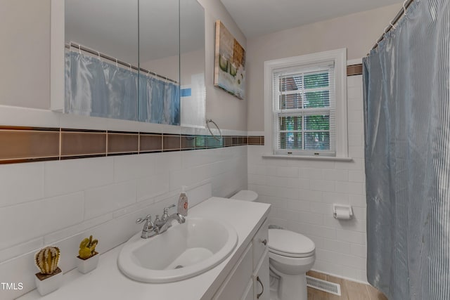 bathroom featuring vanity, toilet, tile walls, a shower with curtain, and visible vents