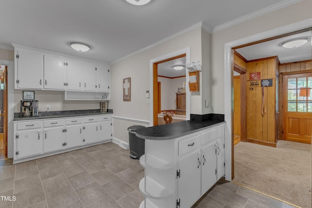kitchen featuring dark countertops, baseboards, white cabinets, a peninsula, and ornamental molding