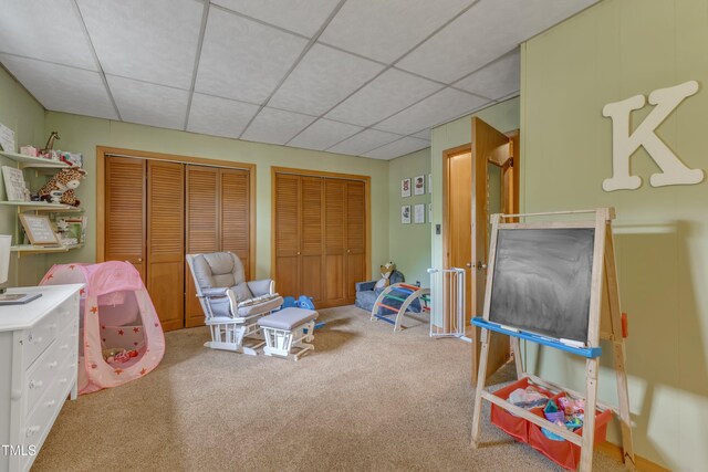 recreation room with carpet floors and a paneled ceiling
