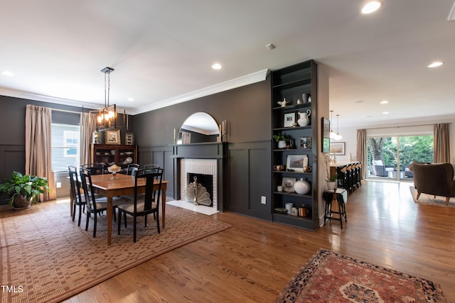 2517 Medway Dr, Raleigh, NC 27608 - dining area featuring crown molding, a fireplace, a decorative wall, arched walkways, and wood finished floors