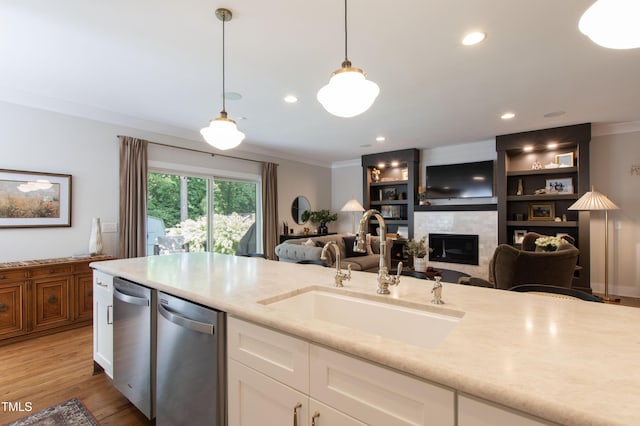 2517 Medway Dr, Raleigh, NC 27608 - kitchen with crown molding, stainless steel dishwasher, a tile fireplace, a sink, and white cabinets