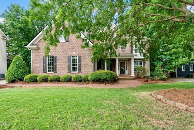 view of front of property featuring brick siding, a front lawn, and cooling unit